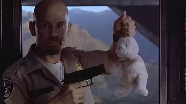 A bald marshal holds up a white rabbit while aiming a handgun inside an aircraft