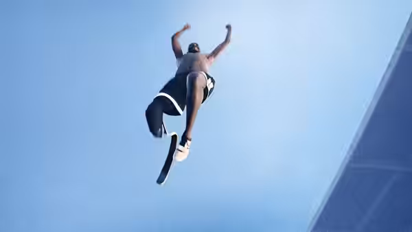 An athlete with a prosthetic leg leaps against a blue stadium backdrop