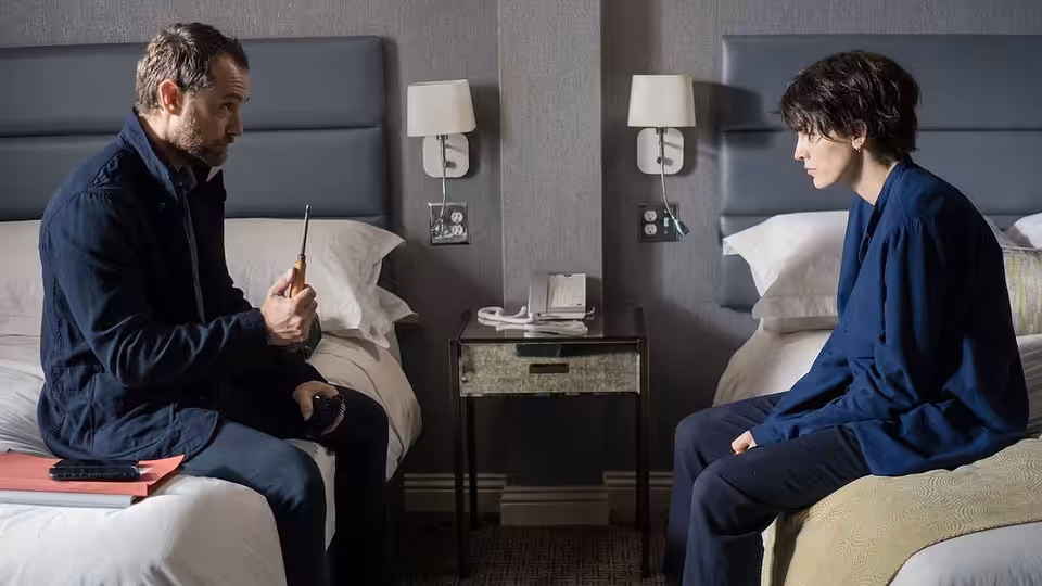 Iain Boyd (Jude Law) sits opposite Stephanie Patrick (Blake Lively) on separate beds