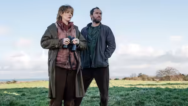 Stephanie Patrick (Blake Lively) holds binoculars beside a bearded man in a field