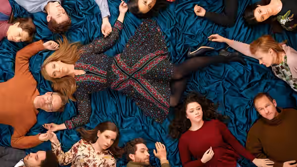 A group of people lie on the floor, arranged in a circle