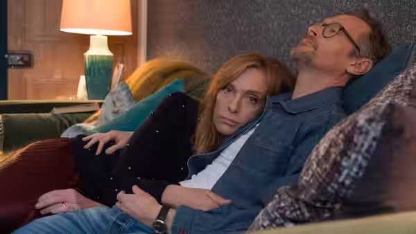 Joy Richards (Toni Collette) reclines beside Alan Richards (Steven Mackintosh) on a sofa