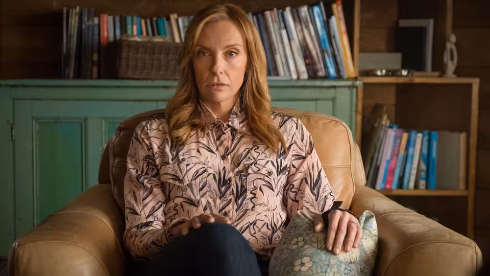 Joy Richards (Toni Collette) sits in an armchair before bookshelves