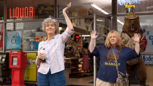 Pearl and Tammy raise their arms inside a liquor store