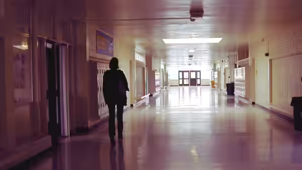 a student walking alone down an empty school hallway