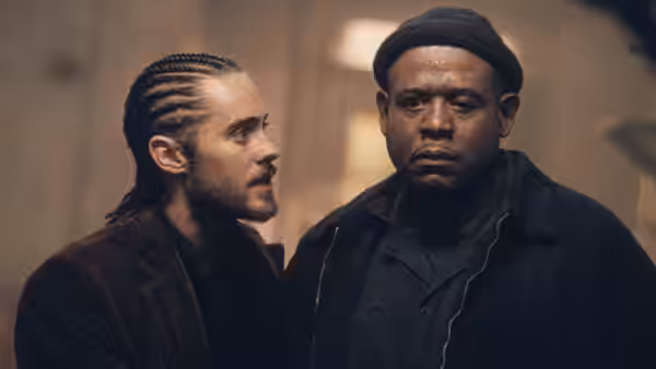 Junior (Jared Leto) stands beside Burnham (Forest Whitaker) in a dim room