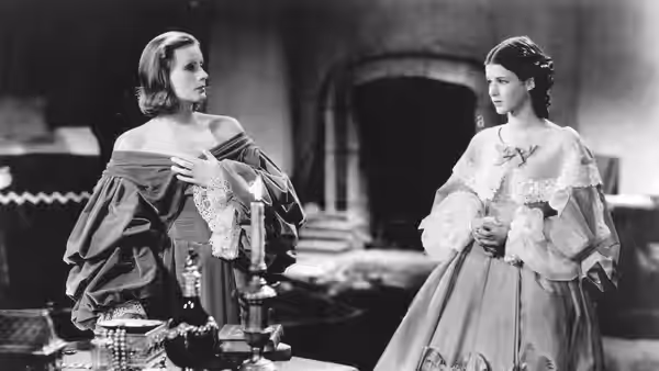 Christina (Greta Garbo) speaks with a woman in a gown inside the palace