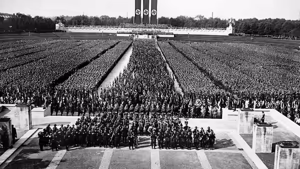 Crowds stand in vast formations across a rally ground