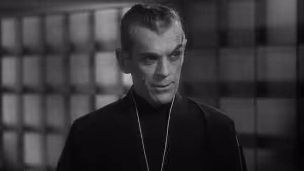 Hjalmar Poelzig (Boris Karloff) stands before a grid-patterned wall