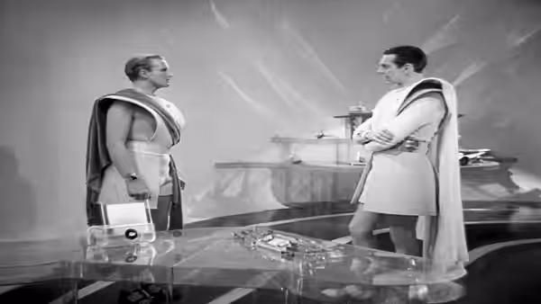 Two men in futuristic robes face each other on a raised platform