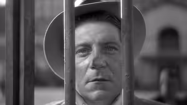 Pépé le Moko (Jean Gabin) peers through the bars of a doorway