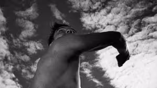 An athlete lifts his arm against a cloudy sky