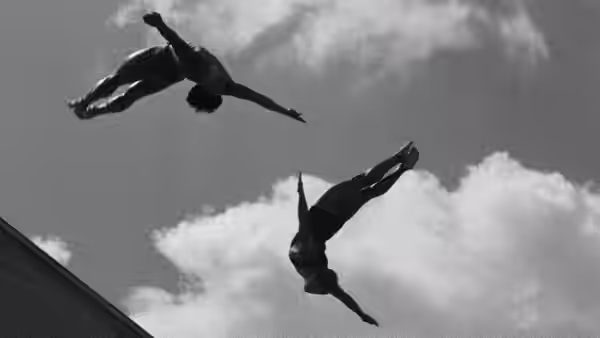 Two athletes twist through the air above the stadium