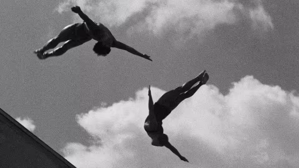 Two athletes twist through the air above the stadium