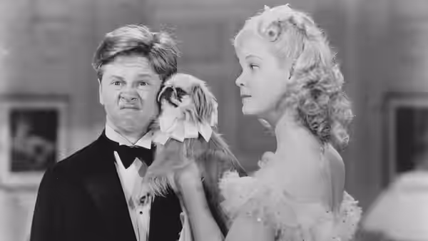 Mickey Moran (Mickey Rooney) and Patsy Barton (Judy Garland) hold a small dog between them