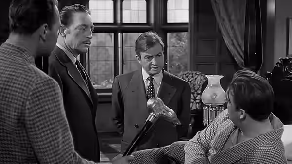 Men gather in a study as one examines a cane