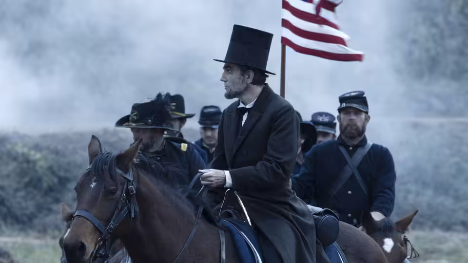 Abraham Lincoln (Daniel Day-Lewis) on horseback with Union soldiers and a flag