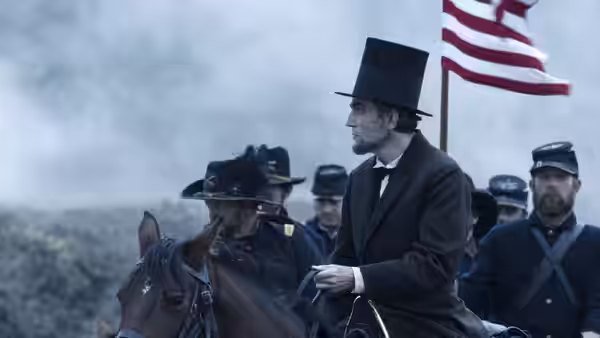 Abraham Lincoln (Daniel Day-Lewis) on horseback with soldiers and an American flag