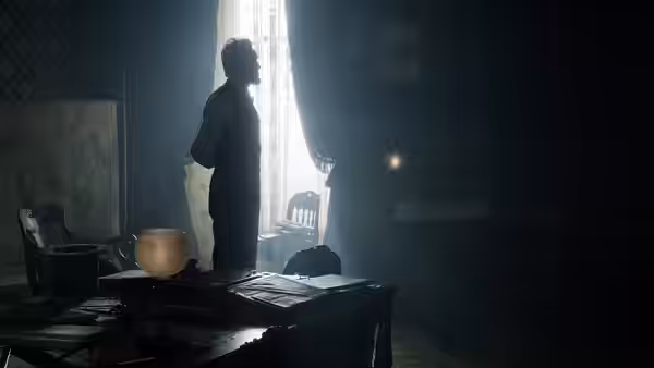 Abraham Lincoln (Daniel Day-Lewis) standing by a window in a dark room