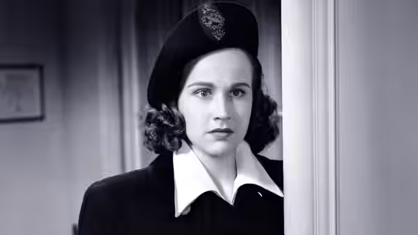 Mary Gibson (Kim Hunter) stands in a doorway wearing a dark uniform and cap