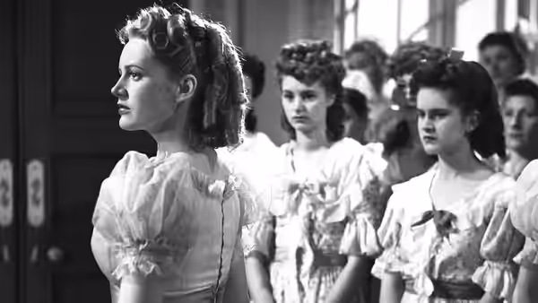 Hesther Shaw Barbary (Margaret Lockwood) stands in profile among young women in matching dresses