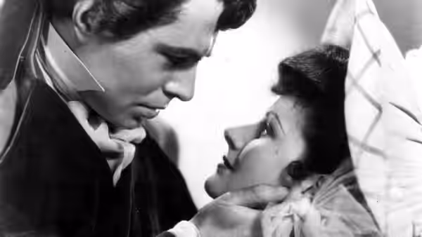 Swinton Rokeby (Stewart Granger) leans close to Clarissa Rohan (Phyllis Calvert) as she reclines