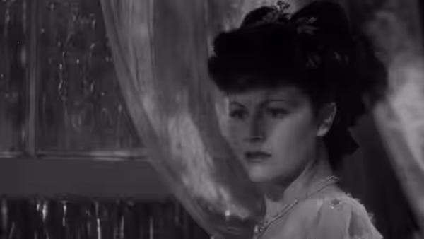 Clarissa Rohan (Phyllis Calvert) stands beside a curtained window in a bonnet