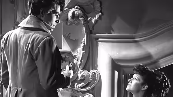 Swinton Rokeby (Stewart Granger) looks down at a seated woman beside an ornate fireplace