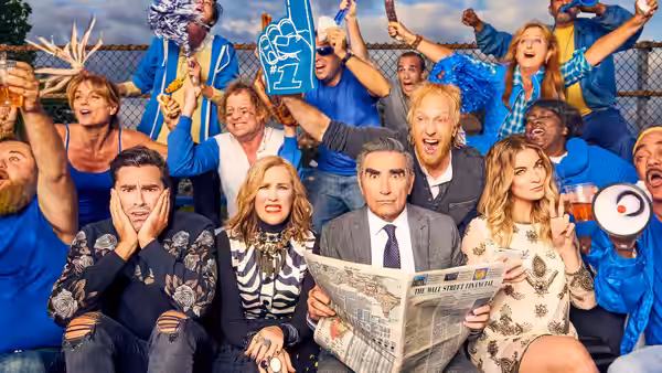 Johnny Rose (Eugene Levy) reads a newspaper while seated with David Rose (Dan Levy) Moira Rose (Catherine O'Hara) and Alexis Rose (Annie Murphy)