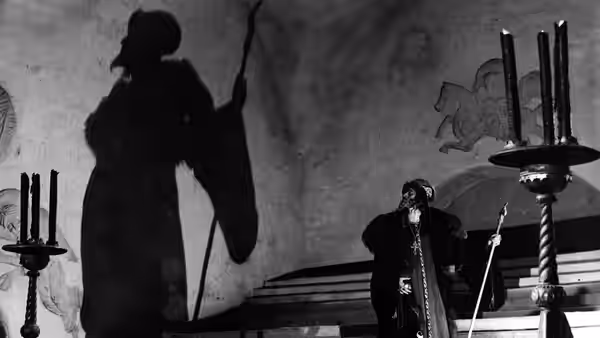 A man stands beside a towering shadow on the palace wall