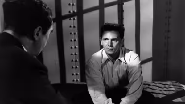 Frank Chambers (John Garfield) leans forward across a table toward a seated man