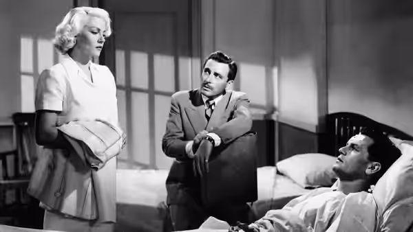 Cora Smith (Lana Turner) stands beside Frank Chambers (John Garfield), who leans on a chair, as Nick Smith (Cecil Kellaway) lies in bed
