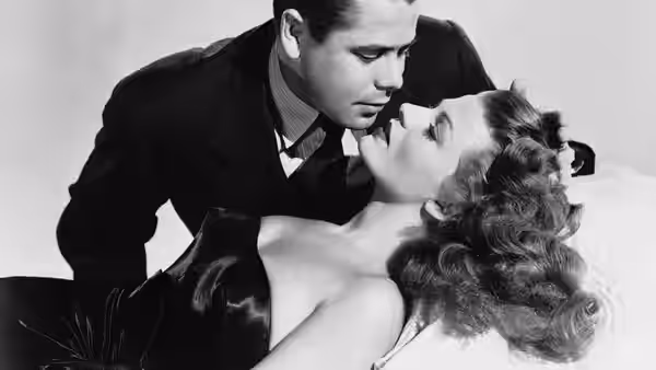 Johnny Farrell (Glenn Ford) leans over Gilda (Rita Hayworth) as she reclines