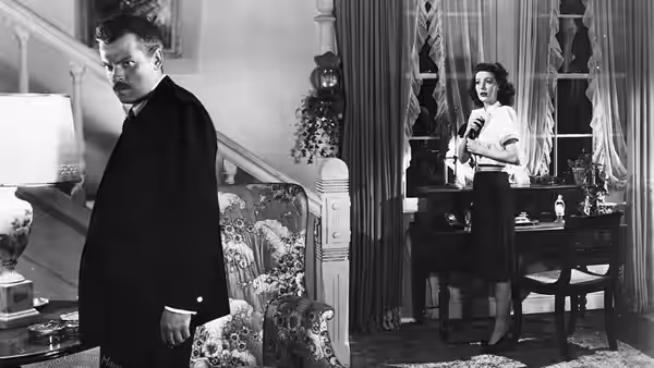 Charles Rankin (Orson Welles) stands across the room from Mary Longstreet (Loretta Young)