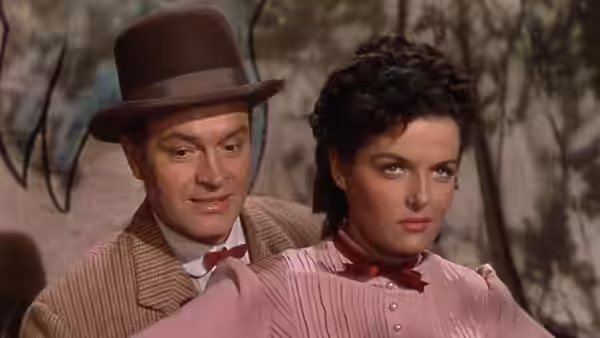Peter Potter sits close behind Calamity Jane as they ride together