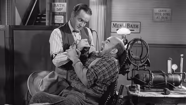 Peter Potter reclines in a barbershop chair as a barber leans over him