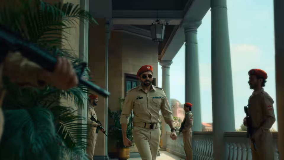 A khaki-uniformed officer in a red beret walks through a station corridor as colleagues watch