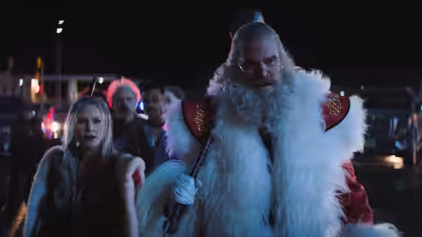 Santa Claus (David Harbour) in a fur-trimmed coat stands with a woman and companions at night