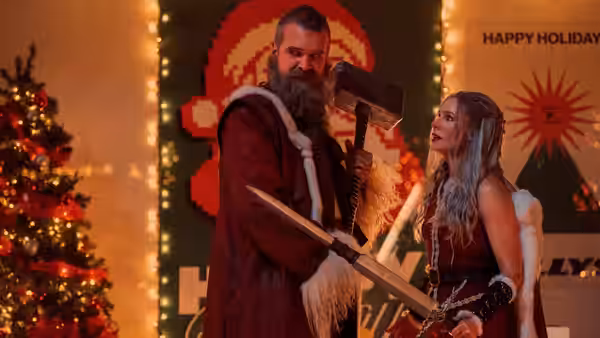 Santa Claus (David Harbour) and a woman hold weapons beside a Christmas tree