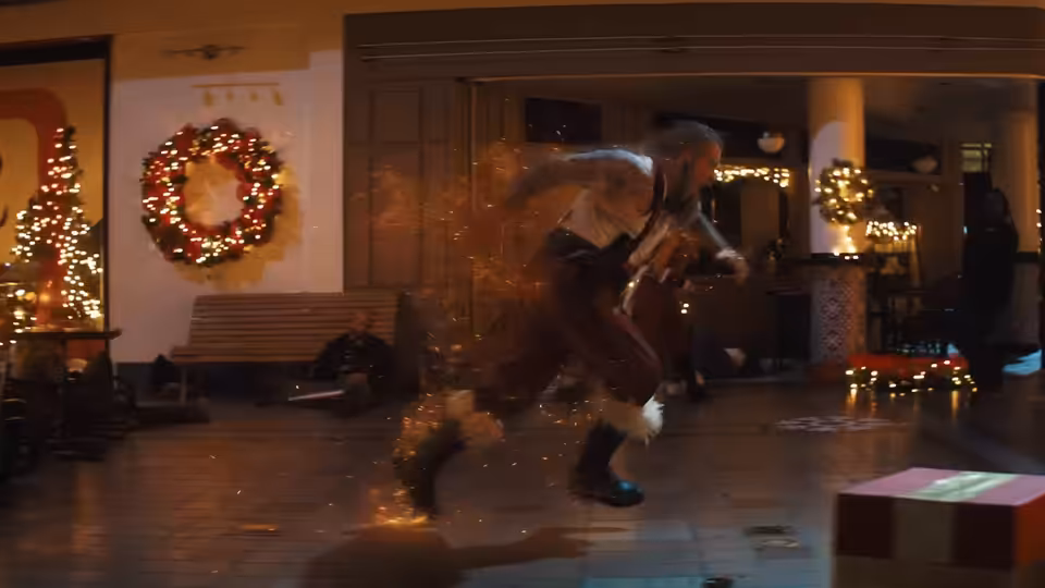 A figure runs past a lit Christmas wreath and festive decorations