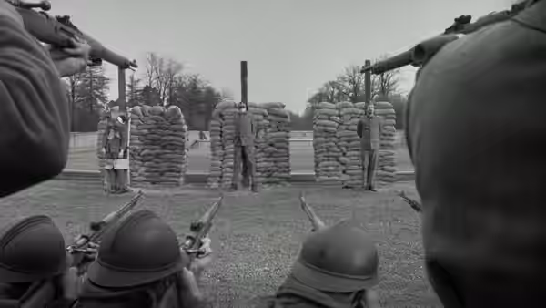 Firing squad aims rifles at men tied to posts