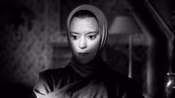 Death (María Casares), wearing a hood, sits inside a car