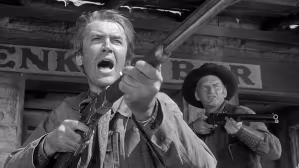 A man shouts while gripping a rifle as another aims from the storefront behind him