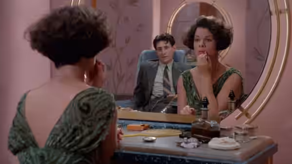 Verna (Marcia Gay Harden) applying lipstick at her vanity with Tom Reagan reflected