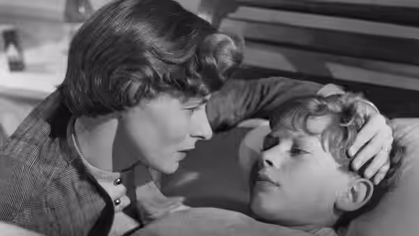 Irene Girard (Ingrid Bergman) leans over her injured son Michele and touches his forehead