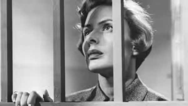 Irene Girard (Ingrid Bergman) looks through vertical bars, one hand gripping a bar