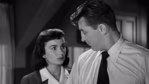 Frank Jessup (Robert Mitchum) and Diane Tremayne (Jean Simmons) look at each other indoors