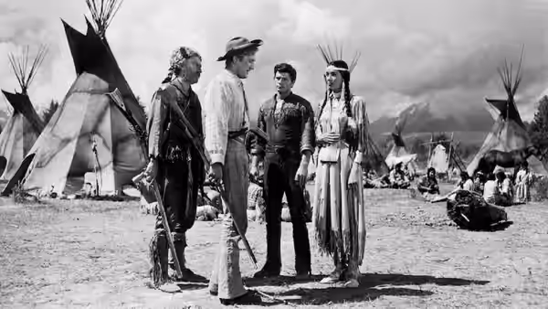 A frontier party stands among tipis at a Native encampment
