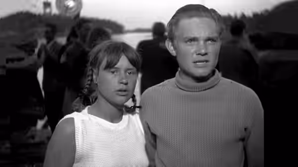 Monika (Harriet Andersson) and Harry (Lars Ekborg) stand among people on a boat
