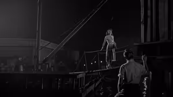 A woman stands on a gangway as a man approaches from below